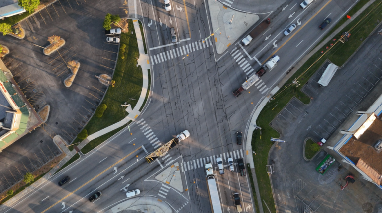 High-angle aerial view of a busy urban intersection with cars and traffic-lines.